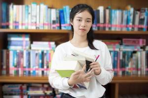 asiatischer Student, der Bücher in der Bibliothek hält foto