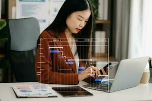 Arbeits- und Aktualisierungsaufgaben des Projektmanagers mit Meilenstein-Fortschrittsplanung und Gantt-Diagramm-Planungsdiagramm. geschäft, das mit smartphone, tablet und laptop im büro arbeitet. foto