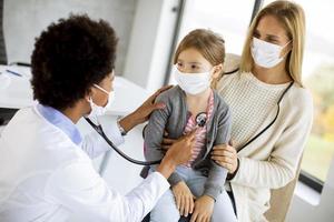 Kinderarzt hört auf die Lunge des Mädchens foto