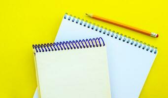 Weiß und Beige Notizblöcke und ein Bleistift auf ein Gelb Hintergrund. foto
