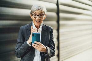 draussen Porträt von erfolgreich reifen Geschäftsfrau Wer ist chatten auf Smartphone. foto