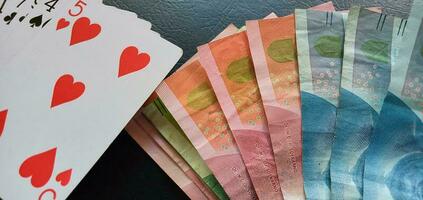 Poker Kombination von Joker Karte mit Rupiahs Banknoten Geld auf schwarz Hintergrund, Kasino Poker, spielen Karte, Glücksspiel foto
