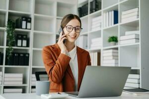 Geschäft kaukasisch Frau reden auf das Telefon und mit ein Laptop mit ein Lächeln während Sitzung beim modern Büro foto