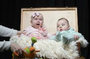 ein wenig Junge und ein Weinen Baby sind Sitzung im ein retro Koffer. erfolglos Foto Session zum jung Kinder.