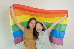 lgbt Gruppe. gut suchen Lesben Paare Lächeln hell Startseite Regenbogen Flaggen. asiatisch jung Paar umarmen jeder andere glücklich, Liebhaber im Liebe, Bisexualität, Homosexualität, Freiheit, Ausdruck foto