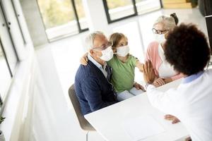 Großeltern und Enkel sprechen mit einem Arzt foto