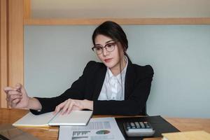 Geschäftsfrauen mit Brille arbeiten im Büro, um die Richtigkeit des Kontos mit einem Taschenrechner zu überprüfen foto