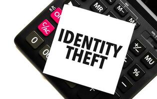 Wörter Identität Diebstahl auf Weiß Aufkleber und Taschenrechner auf Weiß Hintergrund foto