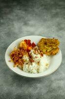 nasi uduk ist ein Stil gedämpft Reis gekocht im Kokosnuss Milch in der Regel gegessen mit Seite Geschirr von Tempeh, Nudeln, Eier, und würzig Kartoffeln, diese Essen ist typisch Essen von Jakarta . foto