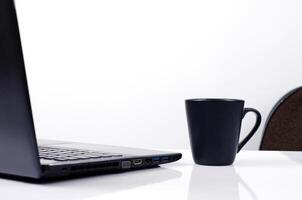 schwarze Kaffeetasse und Laptop auf weißem Hintergrund foto