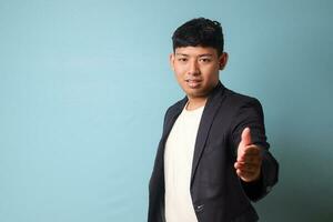 Porträt von jung asiatisch Geschäft Mann im beiläufig passen einladend jemand mit freundlich Hand Gesten und glücklich Ausdruck. isoliert Bild auf Blau Hintergrund foto