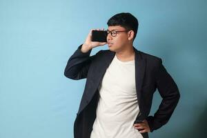 Porträt von jung asiatisch Geschäft Mann im beiläufig passen streiten mit jemand mit leicht genervt Ausdrücke. isoliert Bild auf Blau Hintergrund foto