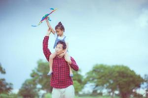 Kind und Vater spielen mit Drachen im Park