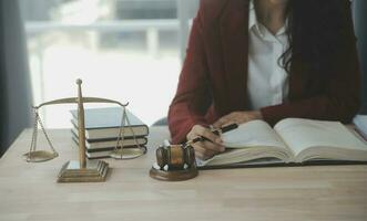 geschäftsleute und anwälte diskutieren vertragspapiere mit messingwaage auf dem schreibtisch im büro. gesetz, juristische dienstleistungen, beratung, justiz und gesetz konzeptbild mit filmkorneffekt foto