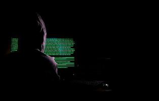 Frauen Hacker bricht in Regierungs-Datenserver ein und infiziert ihr System mit einem Virus an seinem Versteck, dunkelblaue Atmosphäre, Kapuzenfrau mit Laptop mit Binärcode-Hintergrund, Malware-Konzept