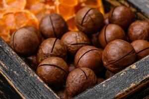 köstlich geröstet Macadamia Nüsse im Schale auf ein dunkel texturiert Hintergrund foto