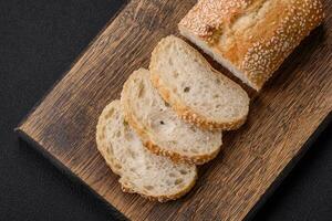 knusprig Weizen Mehl Stangenbrot mit Sesam Saat auf ein hölzern Schneiden Tafel foto