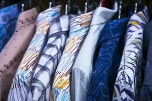 bunt Vielfalt von Hemden Wandbehänge im ein Kleidung Ausstellungsraum. Cluse-up Fokus foto