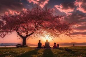 das Silhouette von ein Familie genießen ein Picknick unter ein Kirsche blühen Baum im Sonnenuntergang Himmel. ai generativ foto