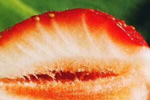Erdbeere Schnitt im Hälfte. Erdbeere Kern. Hälfte von ein Erdbeere auf ein Grün Hintergrund foto