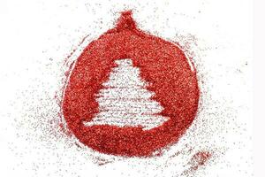 Finger gezeichneter Baum auf glänzendem rotem Konfettihintergrund. Weihnachtsspielzeugball foto