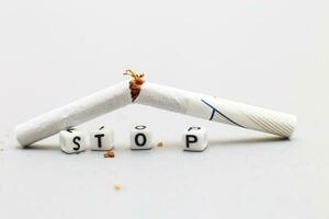 Zerbrochene Zigarette mit dem Wort Stop auf grauem Hintergrund. konzept mit dem rauchen aufhören foto