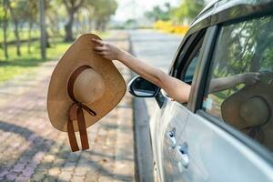 glücklich genießen und Freiheit im Reisen Ausflug mit angehoben Hand und halten Hut draußen von Fenster Auto im Sommer- Ferien Urlaub. foto