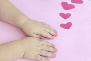 Kinder- Hände auf ein Rosa Hintergrund mit Herzen. das Konzept von das Valentinstag Tag Thema. ein Gruß Karte, ein Erklärung von Liebe. foto