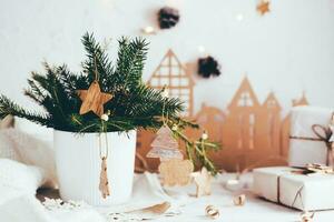 Organisation von ein festlich Weihnachten Tisch. Tanne Strauß im ein Vase dekoriert mit hölzern Ornamente auf das Weihnachten Tisch. umweltfreundlich und hausgemacht Lebensstil foto