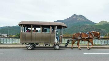 Yufuin, Oita, Kyushu, Japan - - Oktober 14, 2018 das Tourist auf das Pferd Wagen Reiten um Yufuin, Fluss und Yufu Berg Hintergrund foto