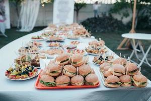 Hochzeitsbuffet mit verschiedenen Snacks und Burgern in der Natur foto