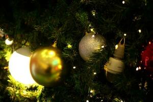 schließen oben Dekoration Ball und Licht Birne auf Weihnachten Baum beim Nacht foto