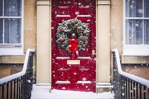 Weihnachten Kranz und Dekoration auf ein klassisch rot Tür auf schneit Winter Urlaub, fröhlich Weihnachten und glücklich Ferien wünscht sich, generativ ai foto