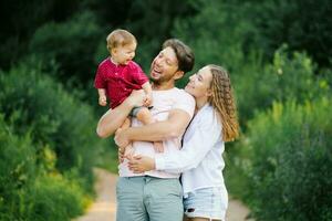 glücklich und froh Familie mit ein jung Sohn Spaziergänge durch das Wald im das Sommer. gesund Lebensstil und glücklich Eltern foto