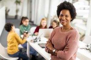 Afroamerikaner-Wissenschaftslehrerin mit Gruppe von Kindern, die elektrisches Spielzeug und Roboter am Robotik-Klassenzimmer programmieren foto