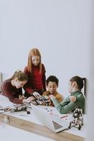 glückliche Kinder, die elektrisches Spielzeug und Roboter im Robotikklassenzimmer programmieren foto
