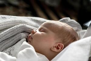 ein Nahaufnahmeporträt eines kleinen Mädchens, das in einer Wiege oder in einem Kinderbett schläft foto