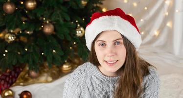 Porträt einer jungen Frau in einem grauen Pullover und Weihnachtsmannhut