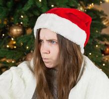 Mädchen in Weihnachtsmütze mit einem unzufriedenen Blick foto