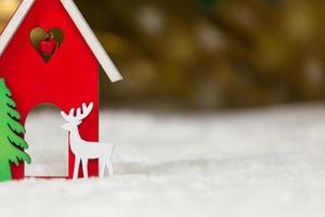 hölzernes hölzernes Spielzeughaushirsch und -baum auf einer weißen Decke, die Schnee imitiert foto