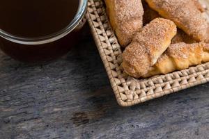 Croissants liegen in einem Weidenkorb mit Teetasse