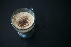 Cappuccino Kaffee im ein Glas Tasse auf das schwarz Hintergrund. foto