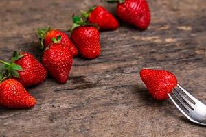 frische Erdbeeren und eine Beere auf Gabelstillleben auf dunklem hölzernem Hintergrund