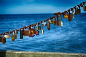Metall rostig Liebe Vorhängeschlösser hing auf das baltisch Seebrücke auf ein Stahl Kette foto