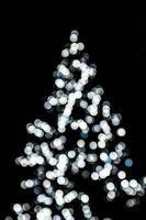 verschwommen Beleuchtung leuchten das Weihnachten Baum auf ein schwarz Hintergrund foto