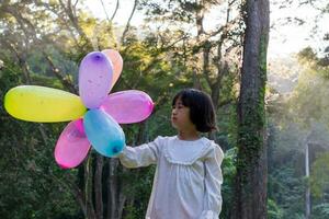 Porträt von Kind Mädchen spielen mit bunt Spielzeug Luftballons im das Park draußen. foto