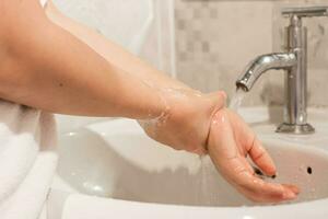 Nahansicht von jung Frau Waschen Hände Über sinken im Badezimmer beim heim. Hygiene Behandlung Konzept foto