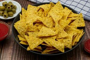 Nachos im ein schwarz Schüssel. Tortilla Chips auf hölzern Hintergrund. foto