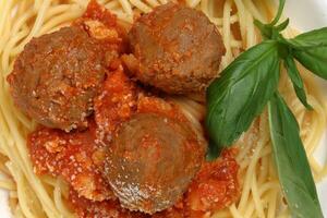 gekocht Spaghetti Tomate Frikadelle Soße Käse Pulver Basilikum auf Weiß Teller hölzern Tabelle foto