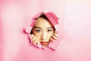 jung schön asiatisch Frau Ausdruck durch zerrissen Papier Loch foto